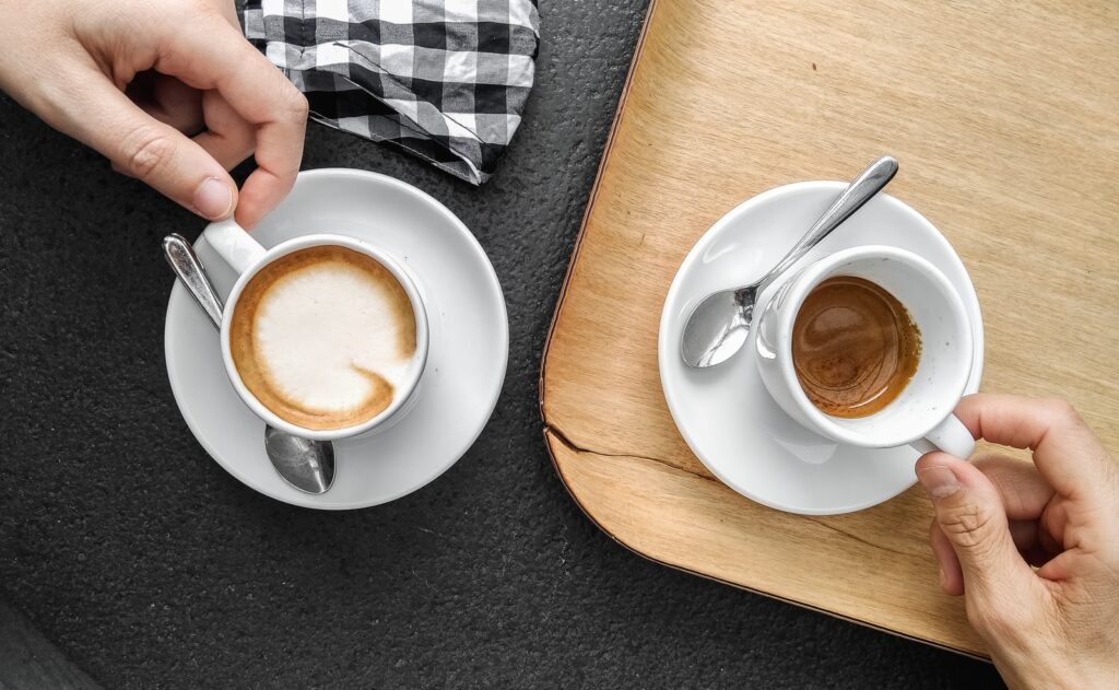 person holding white ceramic mug with brown liquid